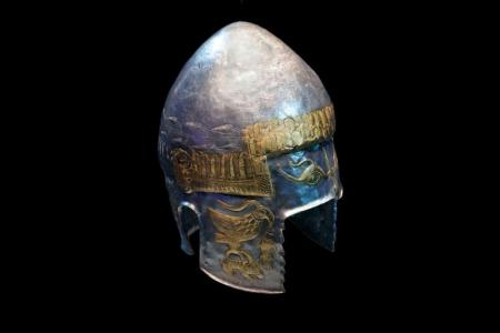 A silver helmet with gold details on a solid black background