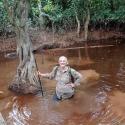 student in the forest waist-deep in water smiling at the camera